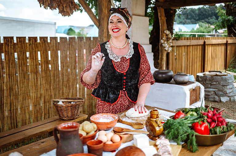 Eine traditionell gekleidete Frau kocht osteuropäische Spezialitäten.